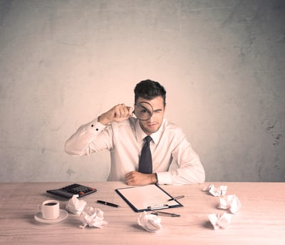 A young office worker sitting at desk working with keyboard, papers, highliter in front of empty clear background wall concept